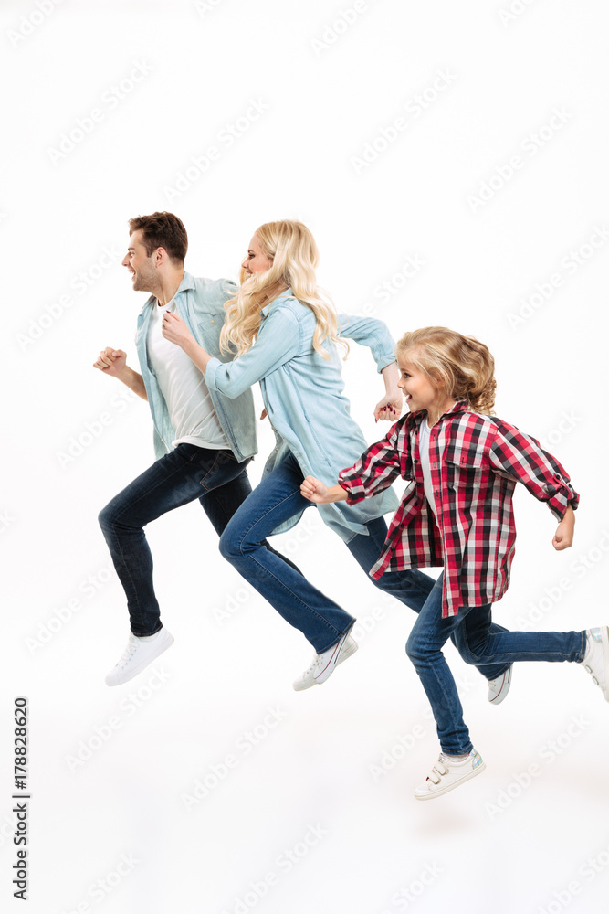 Fototapeta premium Full length portrait of a beautiful young family running