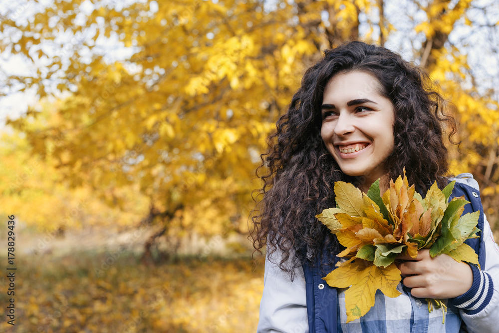 Young model standing in autumn park and holding in hands bunch of leaves. Sexy woman looking sideways. Outdoor. Close up. Autumn. Young model standing in autumn park and holding in hands bunch of leaves. Sexy woman looking sideways. Outdoor. Close up. Autumn.