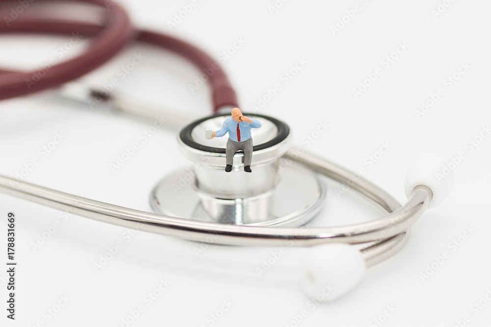 Miniature man sitting on a stethoscope using as health care concept. Miniature man sitting on a stethoscope using as health care concept.