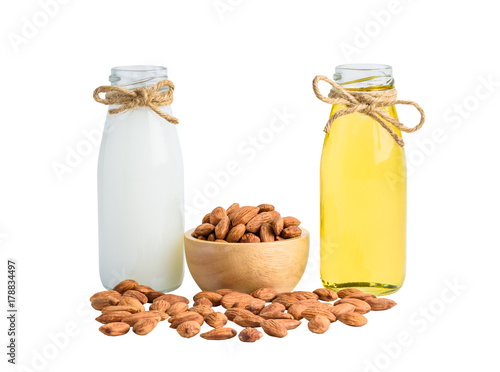 Bottle of almond milk and oil with Peeled almonds in wooden bowl isolated