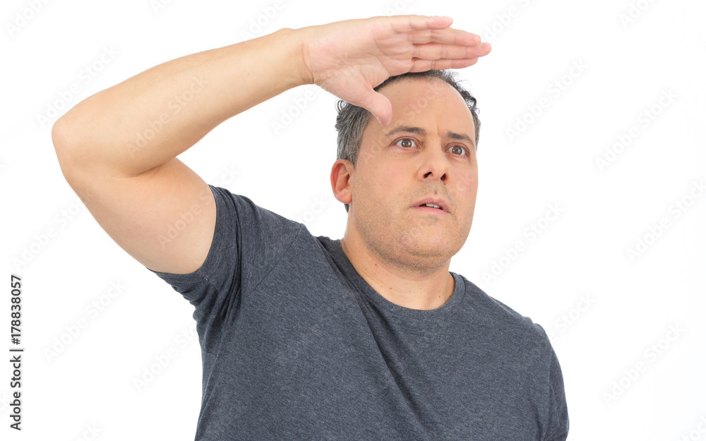 Man puts his hand on his forehead to see further. He is bald, has overweight and wears dark gray T-shirt.. Man puts his hand on his forehead to see further. He is bald, has overweight and wears dark gray T-shirt..