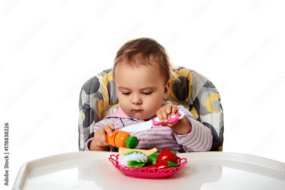 Studio shot of baby playing with toy vegetables. Isolated on white background. Studio shot of baby playing with toy vegetables. Isolated on white background.