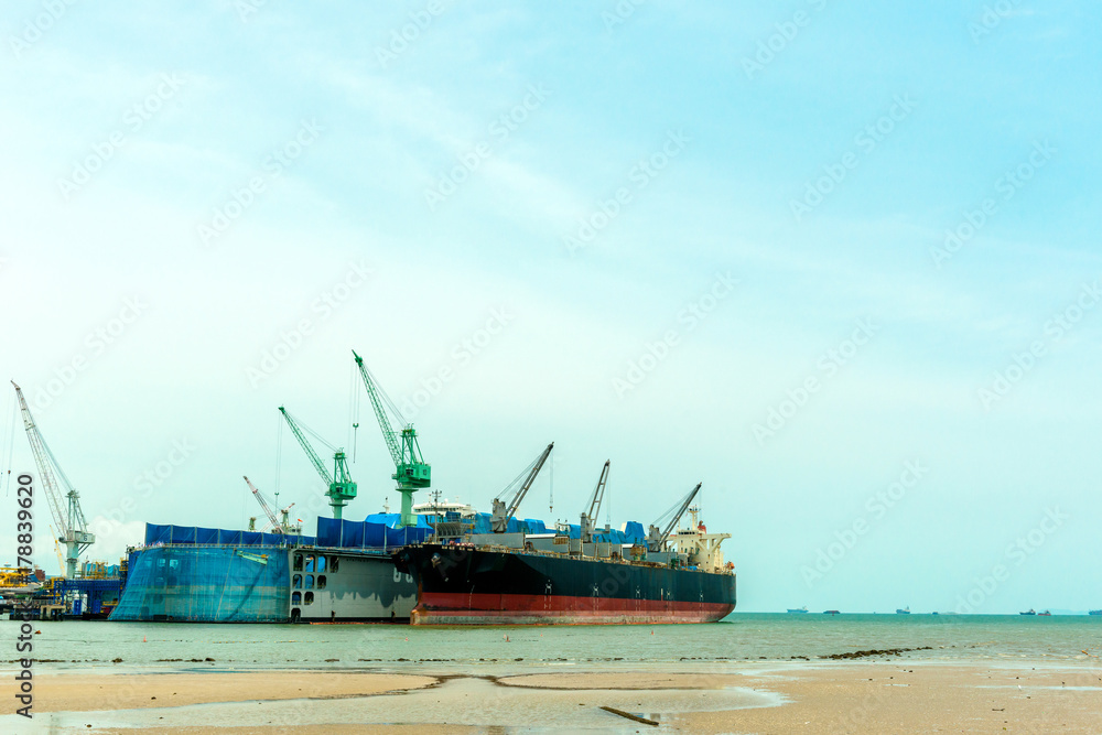 Fototapeta premium Large ship building site dry dock with cargo ship dock next to it.