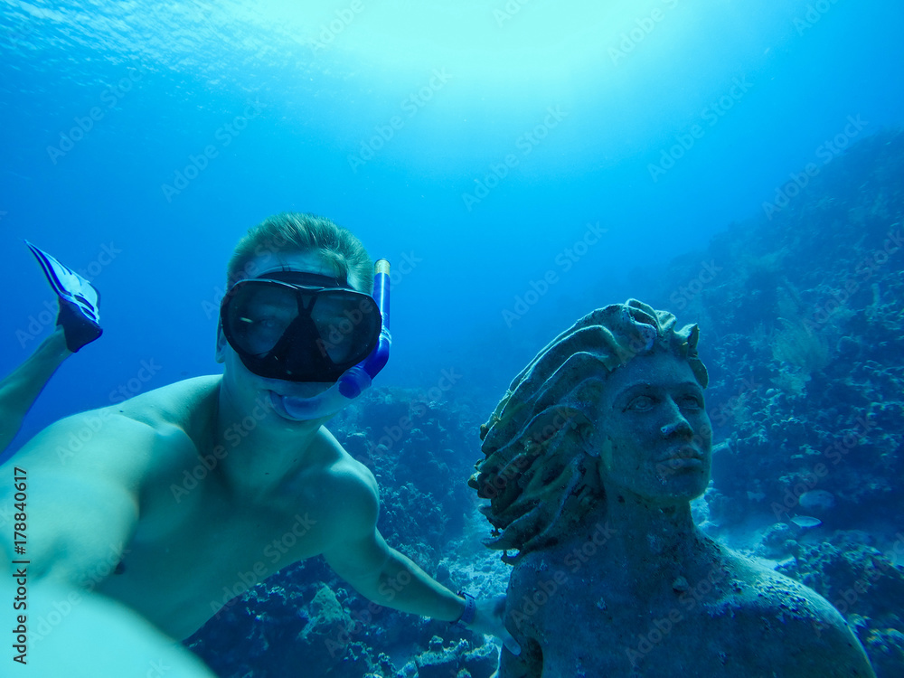 Underwater wide angle selfie of muscular freediver with the mermaid