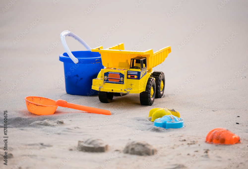 Obraz premium Beach toys series. The yellow truck, blue tank and scoop device. On the beach in holiday concept.