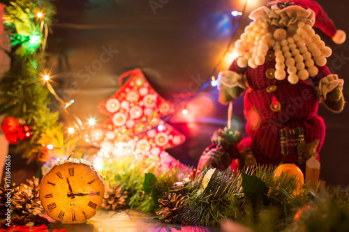 Новогодние декорации. Деревянные часы на фоне новогодних гирлянд и Санта Клауса. Начало двенадцатого. Канун нового года