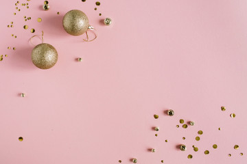 Golden confetti and Christmas toy balls on pink background. Flat lay, top view holiday background.