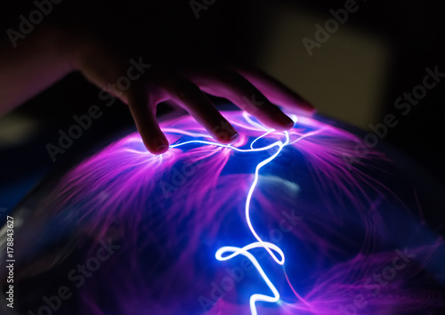 Woman's hand touching plasma globe.