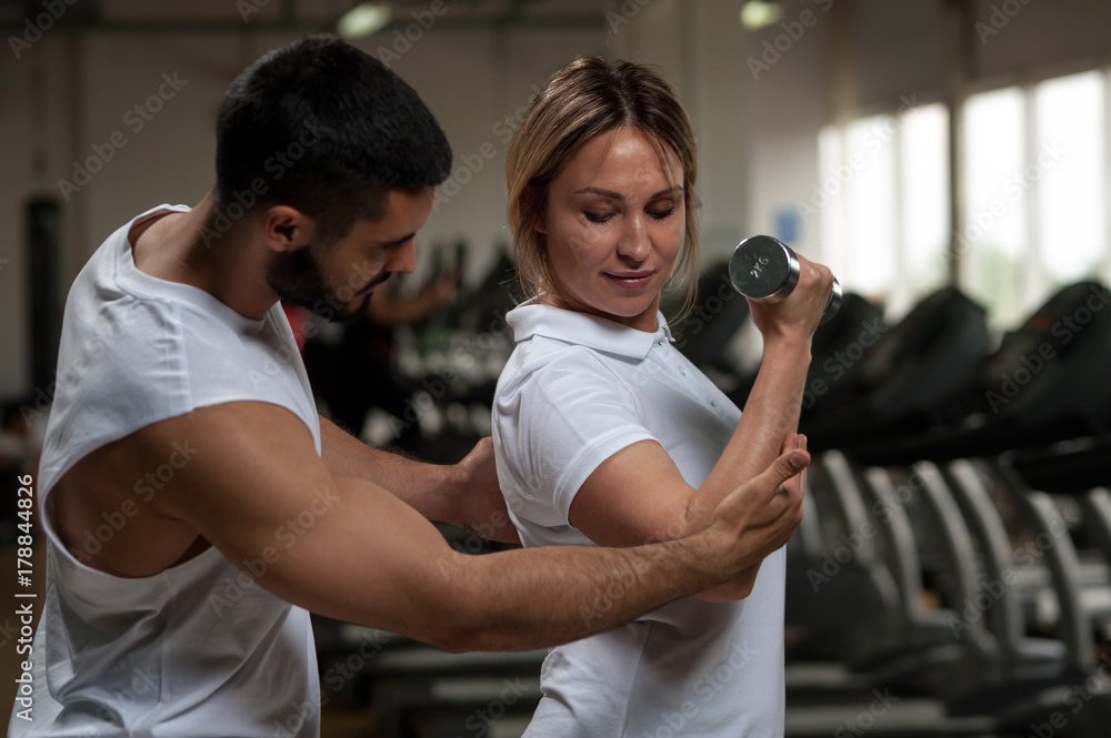 Middle aged woman working out with coach in gym Middle aged woman working out with coach in gym