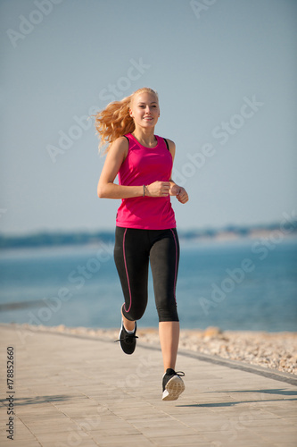 jogging in th beach - woman runns near sea on early summer morning