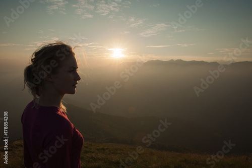 Woamn stands on a peak of mountain at sunset