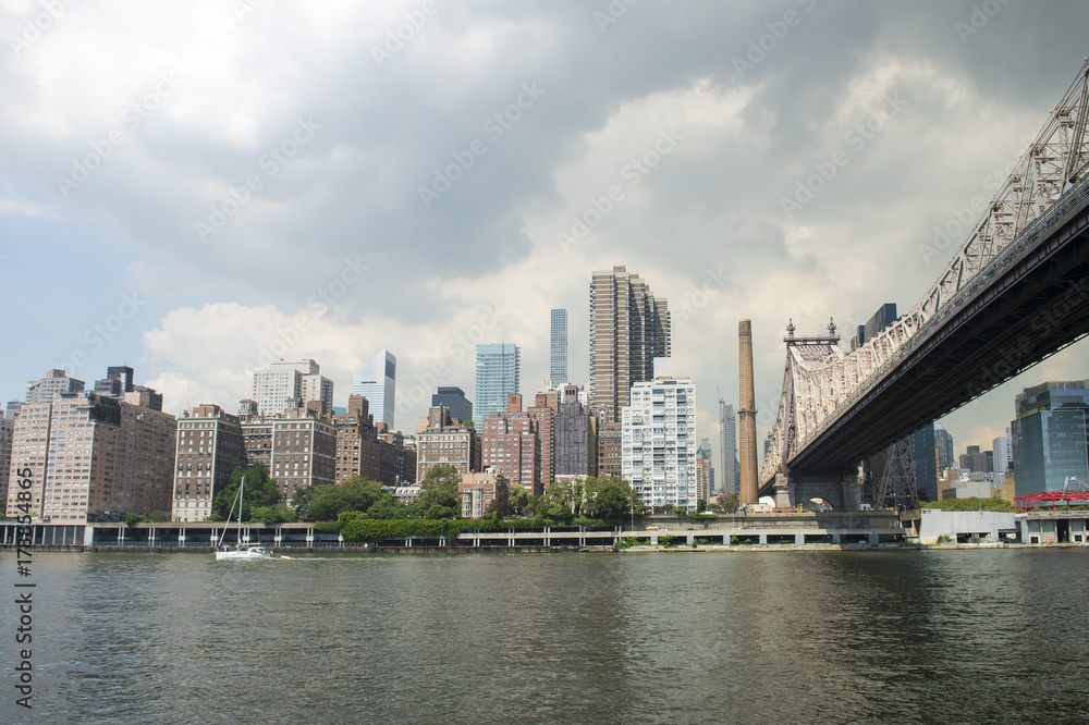 New York City and Queensboro Bridge skyline viewed across the East River from Roosevelt Island waterfront.