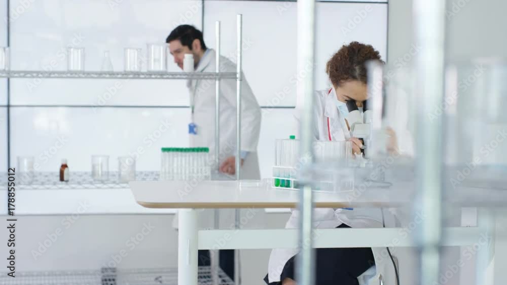 Research scientist working in laboratory, looking at sample under microscope. Research scientist working in laboratory, looking at sample under microscope.