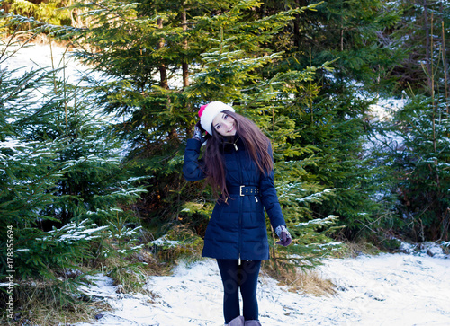 Happy girl in Christmas hat standing in the cold and smiling