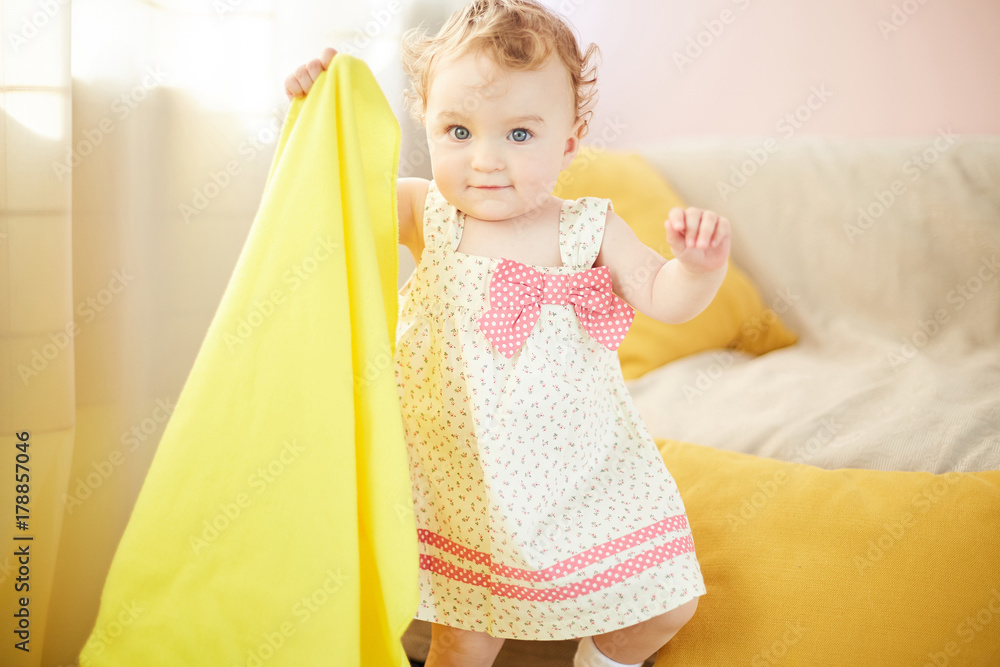 little child is playing in his room with a yellow blanket little child is playing in his room with a yellow blanket