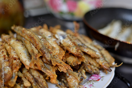 Fried smelt in a frying pan on the table with spices, lime and thyme. Small crispy fish. Selective focus