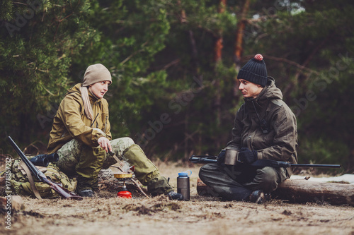 Two hunters are eating together in the forest. Bushcraft, hunting and people concept
