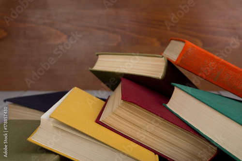 Back to school and education concept - heap colorful hardback books on table on brown wooden background