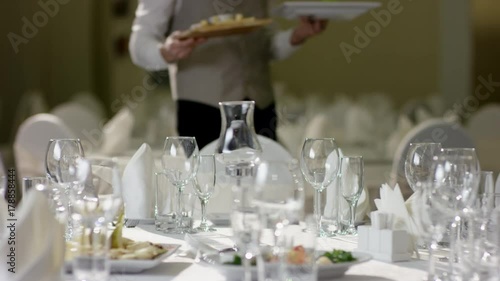 Shot of professional waiter serving dessert and vegetables to dinner table at restaurant photo