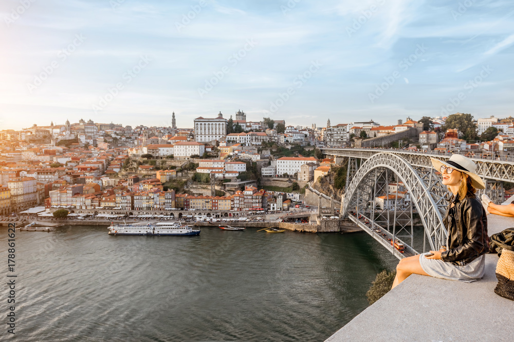 Young woman tourist enjoying great view on the old town and river in Porto city during the sunset in Portugal Young woman tourist enjoying great view on the old town and river in Porto city during the sunset in Portugal