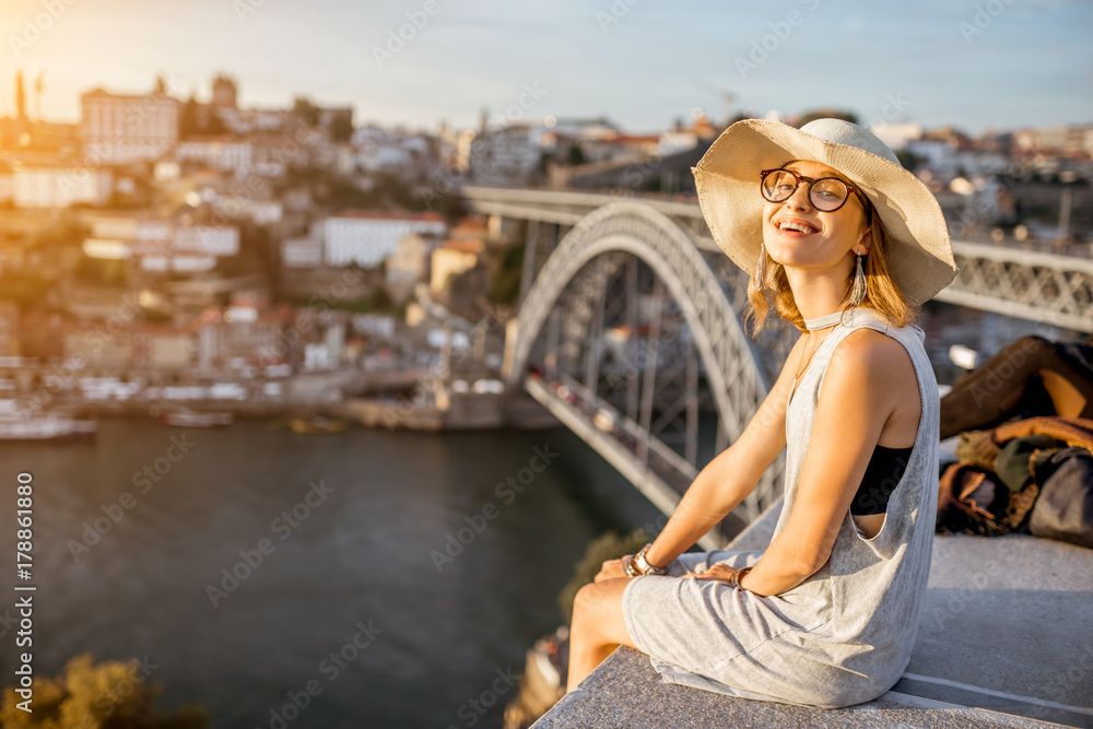 Lifestyle portrait of a young woman tourist enjoying great view on the old town and river in Porto city during the sunset in Portugal