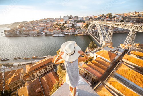 Young woman tourist enjoying beautiful landscape view on the old town with river and famous iron bridge during the sunset in Porto city, Portugal photo