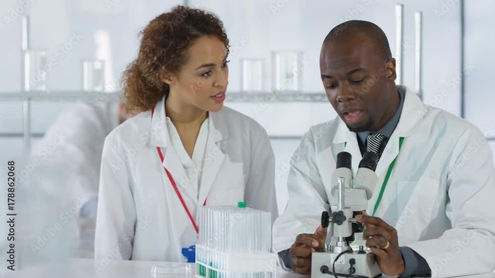 Scientific research team in white coats working in lab & discussing analysis. Scientific research team in white coats working in lab & discussing analysis.