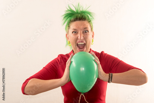 A girl with green hair is holding an air ball in her hands. © galitsin