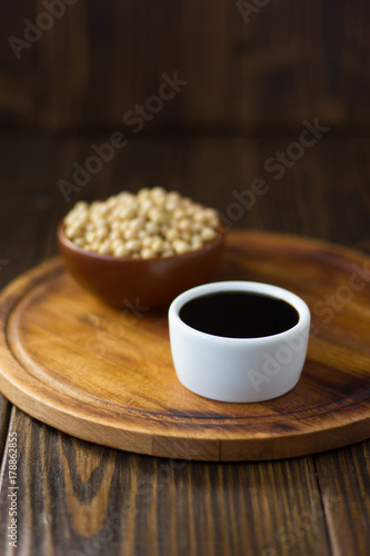 Soy sauce in a white ceramic bowl over wooden board.