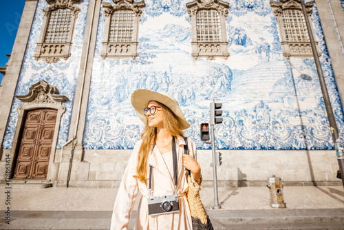 Young woman tourist walking near the church with famous portuguese blue ceramic tiles on the facade traveling in Porto city, Portugal