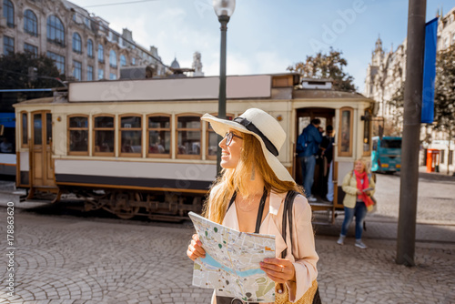 Lifestyle portrait of a woman with paper map near the famous old touristic tram on the street in Porto city, Portugal