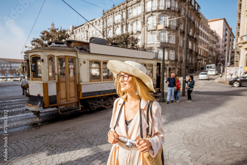 Lifestyle portrait of a woman with photo camera near the famous old touristic tram on the street in Porto city, Portugal