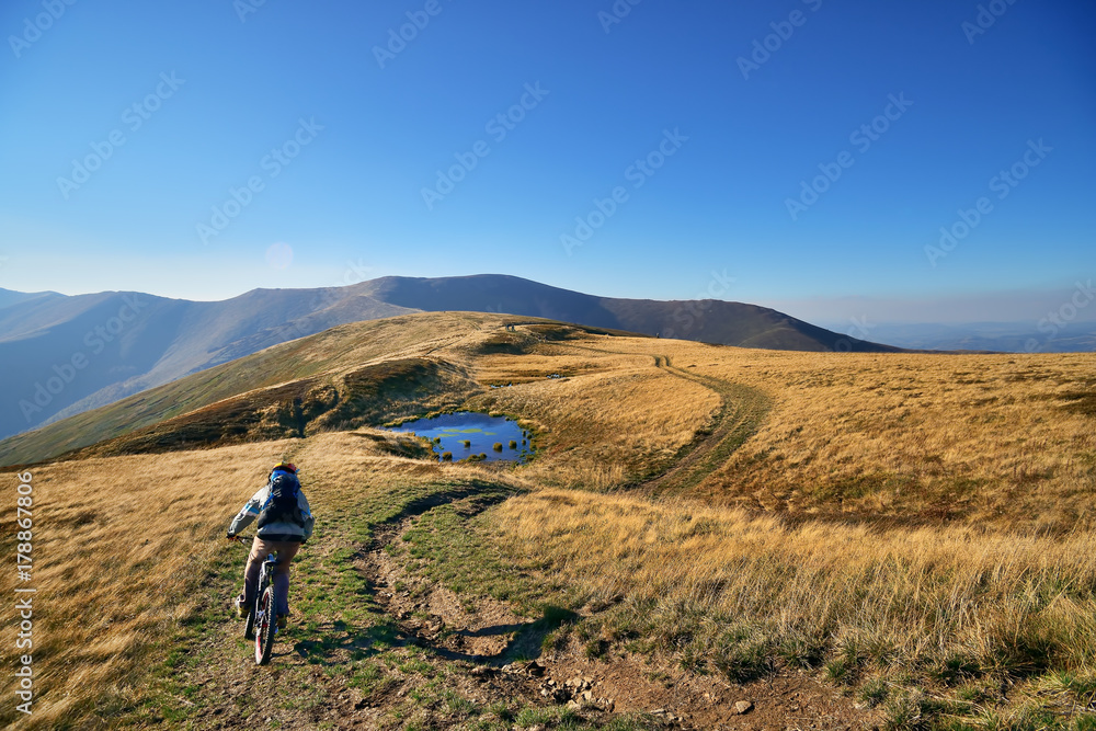 Mountain bikers riding the mountain bikes on the trail to horizon line against beautiful fall mountain landscape.  Extreme sport concept.