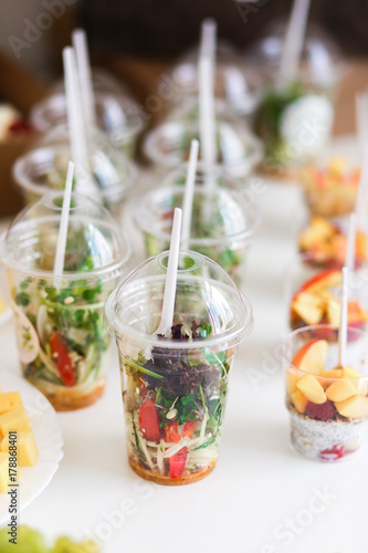 Mini desserts and microgreen salad canapes vegetable snacks in plastic cups canaps. Catering arranged table