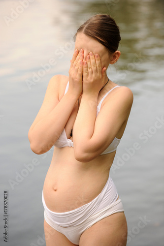 A semi-nude Caucasian girl resting on the lake during pregnancy. The concept of a healthy lifestyle. Lingerie for pregnant women. photo