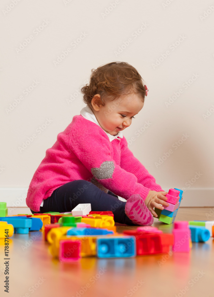 Toddler baby girl playing with rubber building blocks.