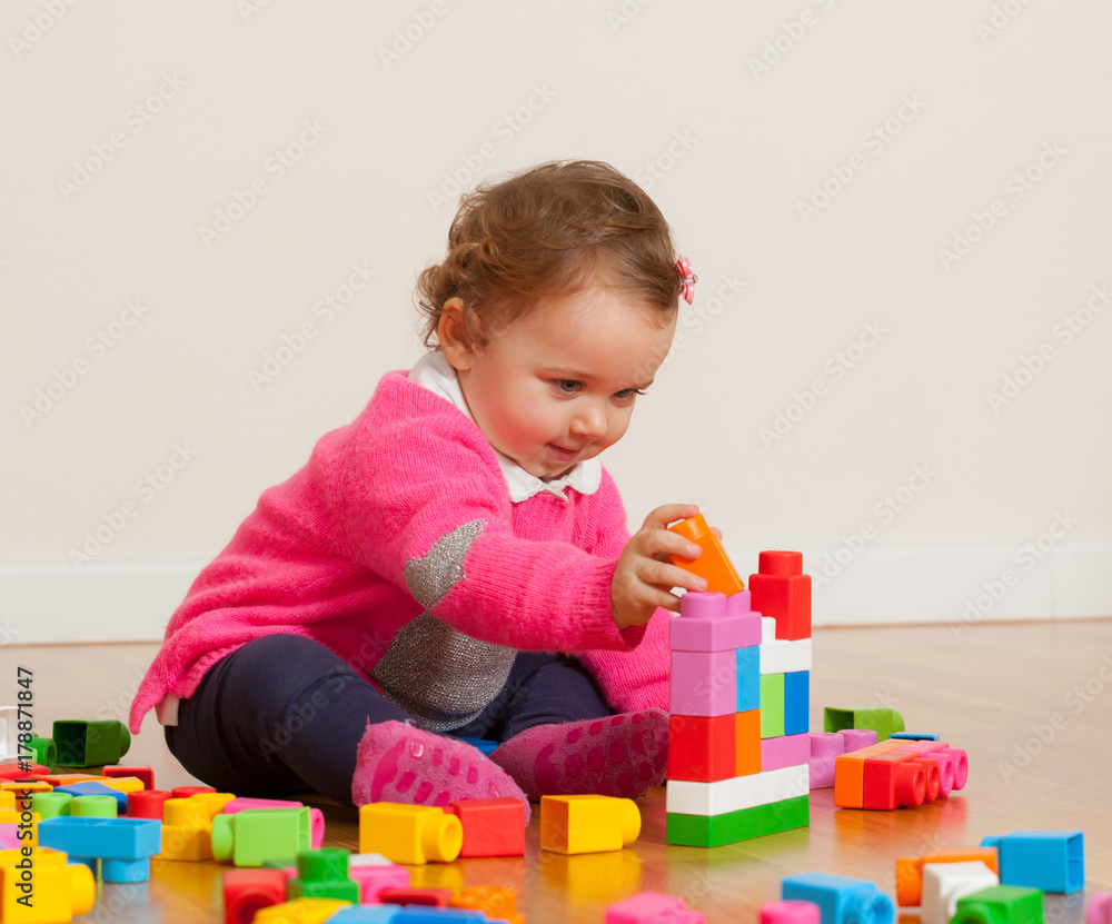 Obraz premium Toddler baby girl playing with rubber building blocks.