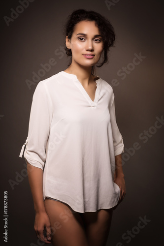 Young beautiful woman, brunette, in a white shirt with bare legs