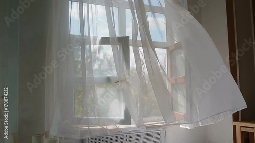 Open window with white curtain moving on the wind. Tranquil background.
