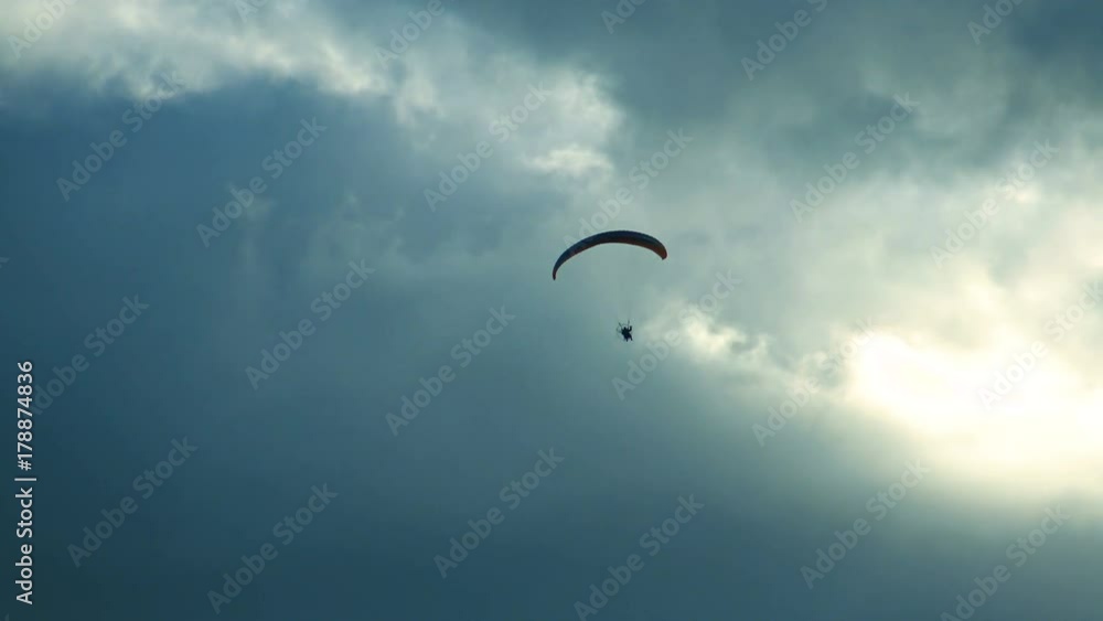 Paraglider flies in the clouds. Air sport and recreation. A powered paraglider - a glider with a dorsal power plant, providing the rise and moving in the air. Paraglider flies in the clouds. Air sport and recreation. A powered paraglider - a glider with a dorsal power plant, providing the rise and moving in the air.