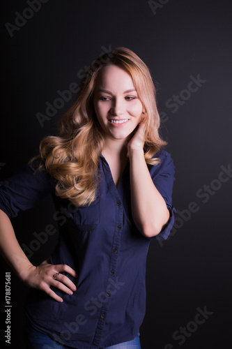 Romantic young model with long blonde hair wears shirt and jeans,  posing on a black background © vpavlyuk