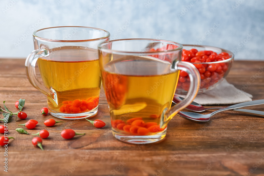 Cups with goji tea on wooden table Cups with goji tea on wooden table