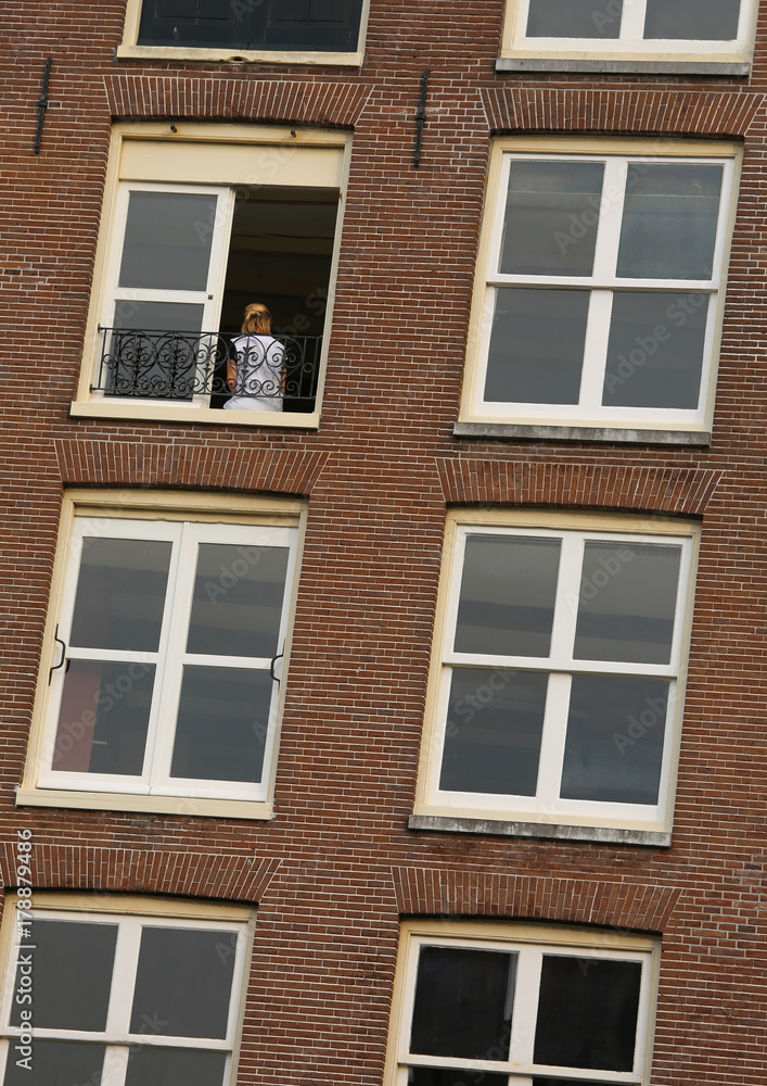 blonde girl at the apartment building window in an european city