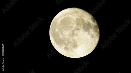 Bright Almost Full-Moon with many craters in a dark sky.