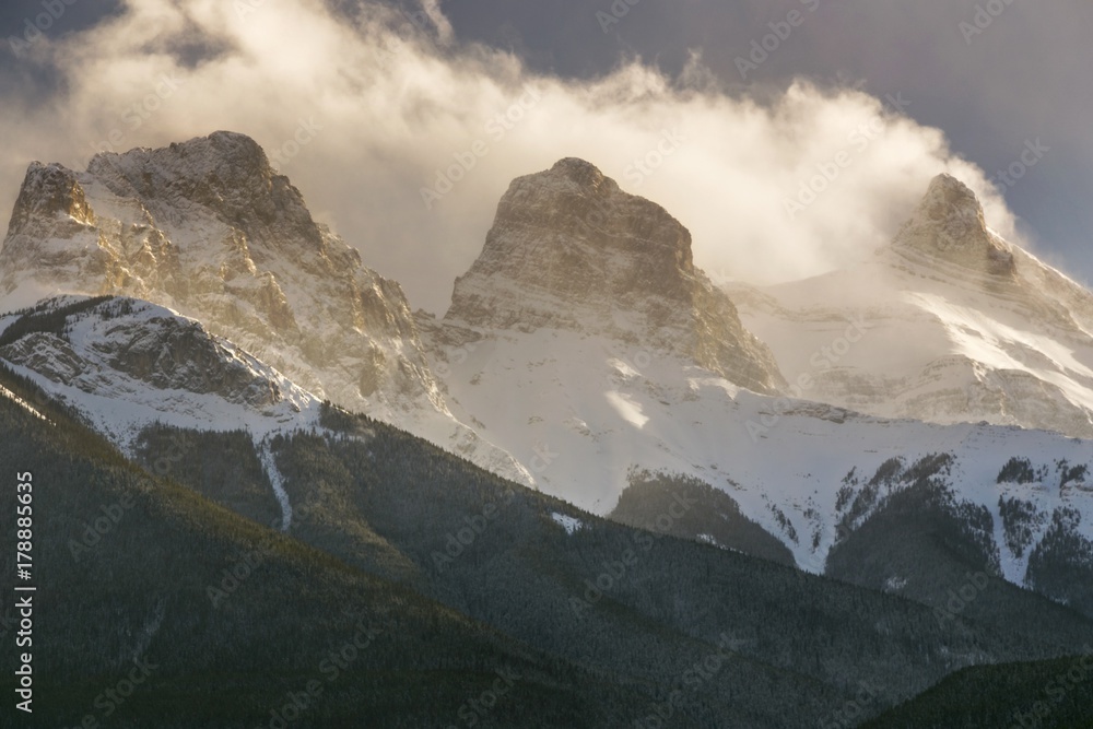 Dramatic Sky and Low Clouds over Snowcapped Three Sisters Mountain near Canmore in Alberta Foothills of Canadian Rockies