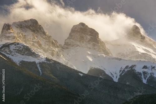 Dramatic Sky and Low Clouds over Snowcapped Three Sisters Mountain near Canmore in Alberta Foothills of Canadian Rockies
