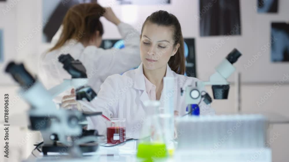 Scientific research team working in the lab, focus on woman experimenting with chemicals Scientific research team working in the lab, focus on woman experimenting with chemicals