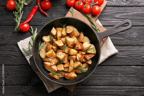 Composition with delicious rosemary potatoes in pan on table