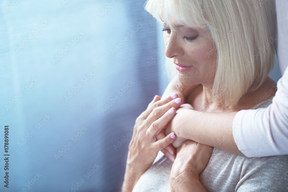 Mature and young women hugging indoors. Elderly care concept Mature and young women hugging indoors. Elderly care concept