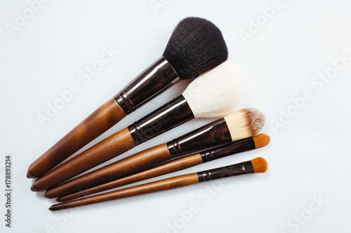 Makeup products and brushes on white background